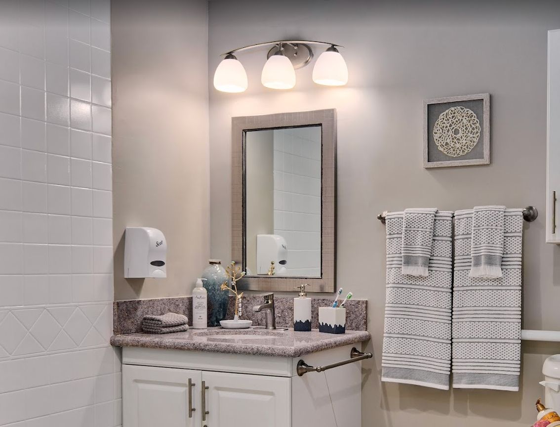 A well-organized bathroom with a mirror, light fixtures, and towels.