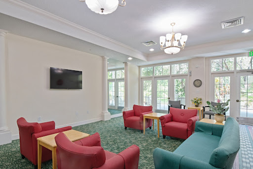 A cozy lounge area featuring red chairs and a television, illuminated by natural light.