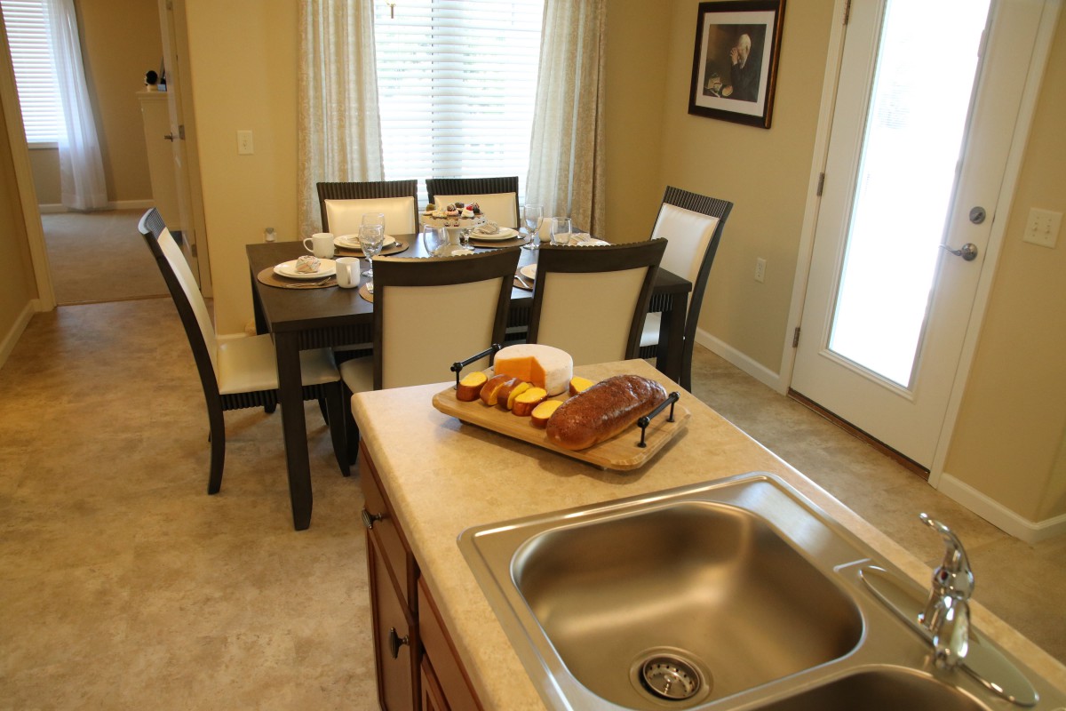 A cozy kitchen and dining area with a countertop, sink, and a neatly set dining table.