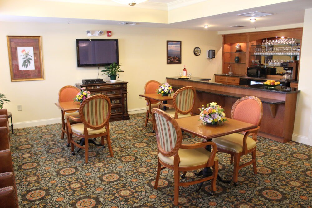 A cozy dining area with tables, chairs, and a television on the wall.