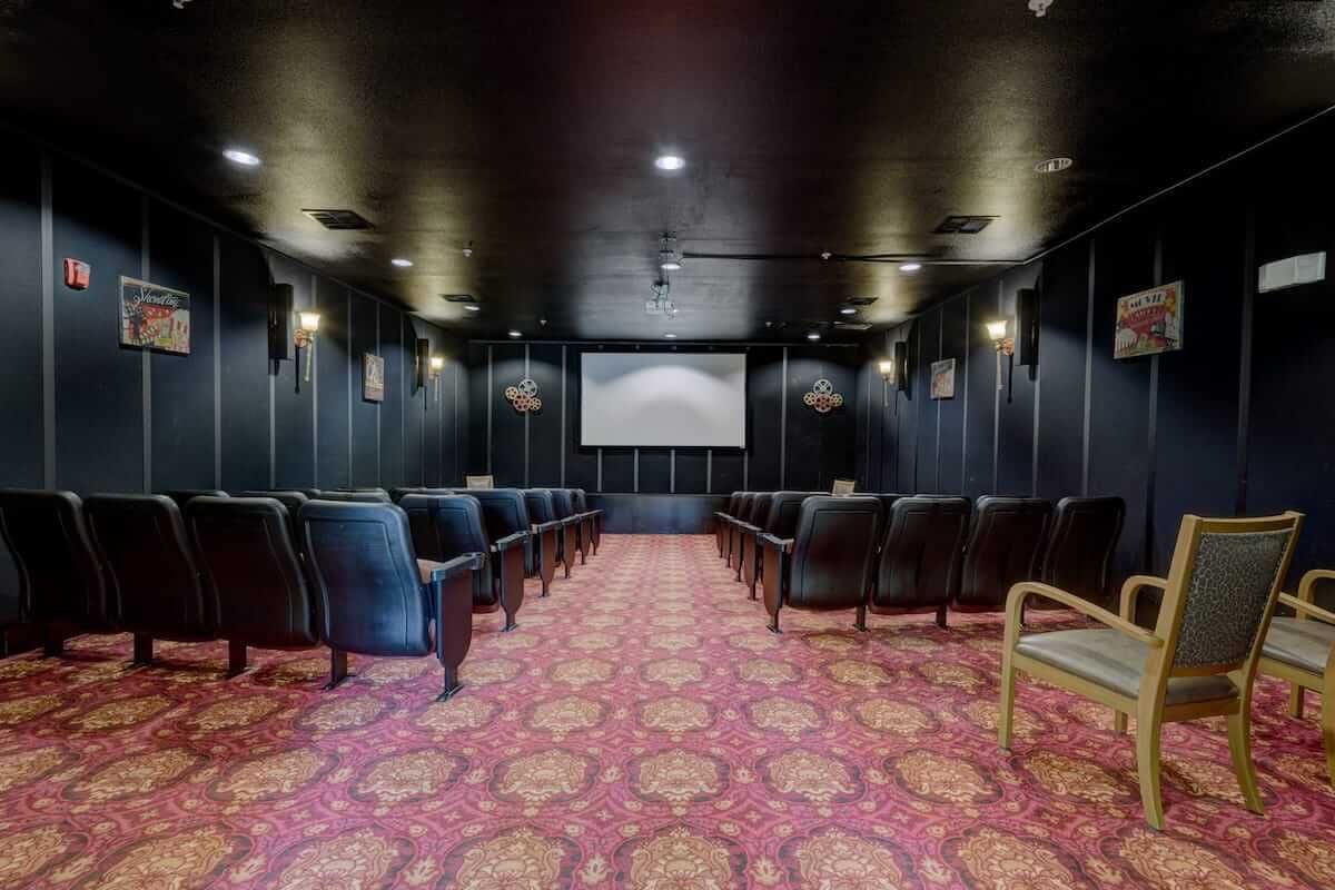 A small, luxurious theater room with rows of comfortable seating and a large screen.