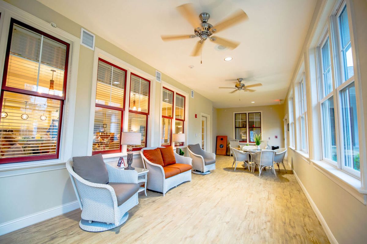 A bright and airy living space with comfortable seating, ceiling fans, and large windows.