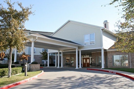 A building with a covered entrance supported by columns, captured on a clear day.