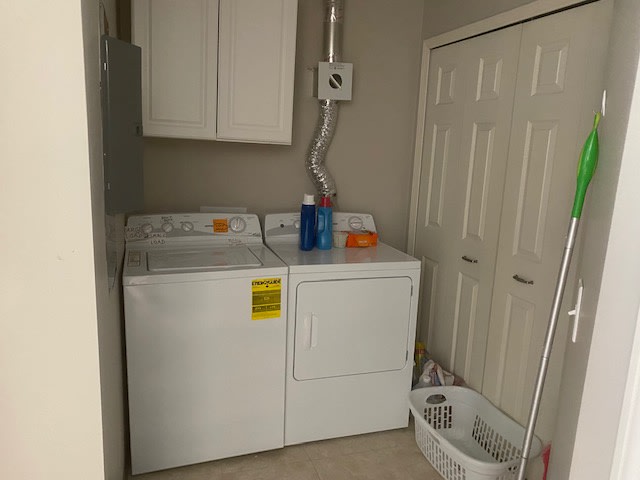 A small laundry room with a washer and dryer, detergent, and a clothes basket.