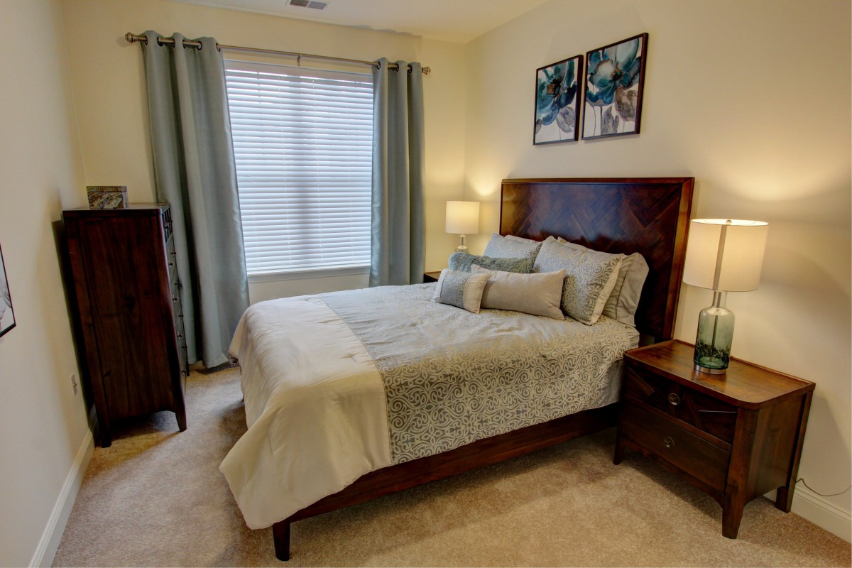 A cozy bedroom featuring a neatly made bed, wooden furniture, and soft lighting.