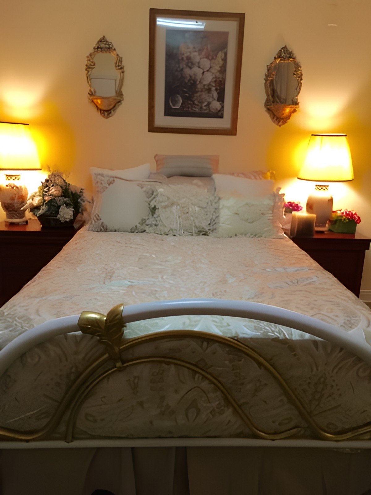A cozy bedroom with a neatly made bed, flanked by two glowing lamps on wooden nightstands.