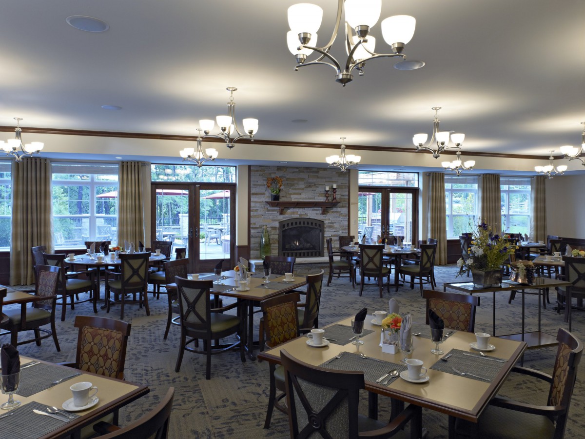 A spacious dining room with elegant chandeliers and neatly arranged tables and chairs.