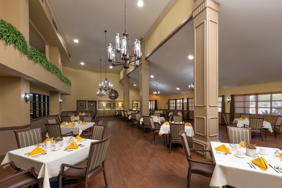 A spacious restaurant dining area with elegant chandeliers and neatly set tables.