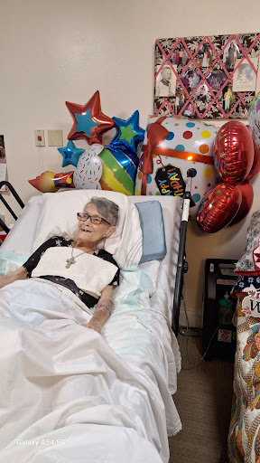 An elderly patient surrounded by colorful balloons, celebrating a special occasion.