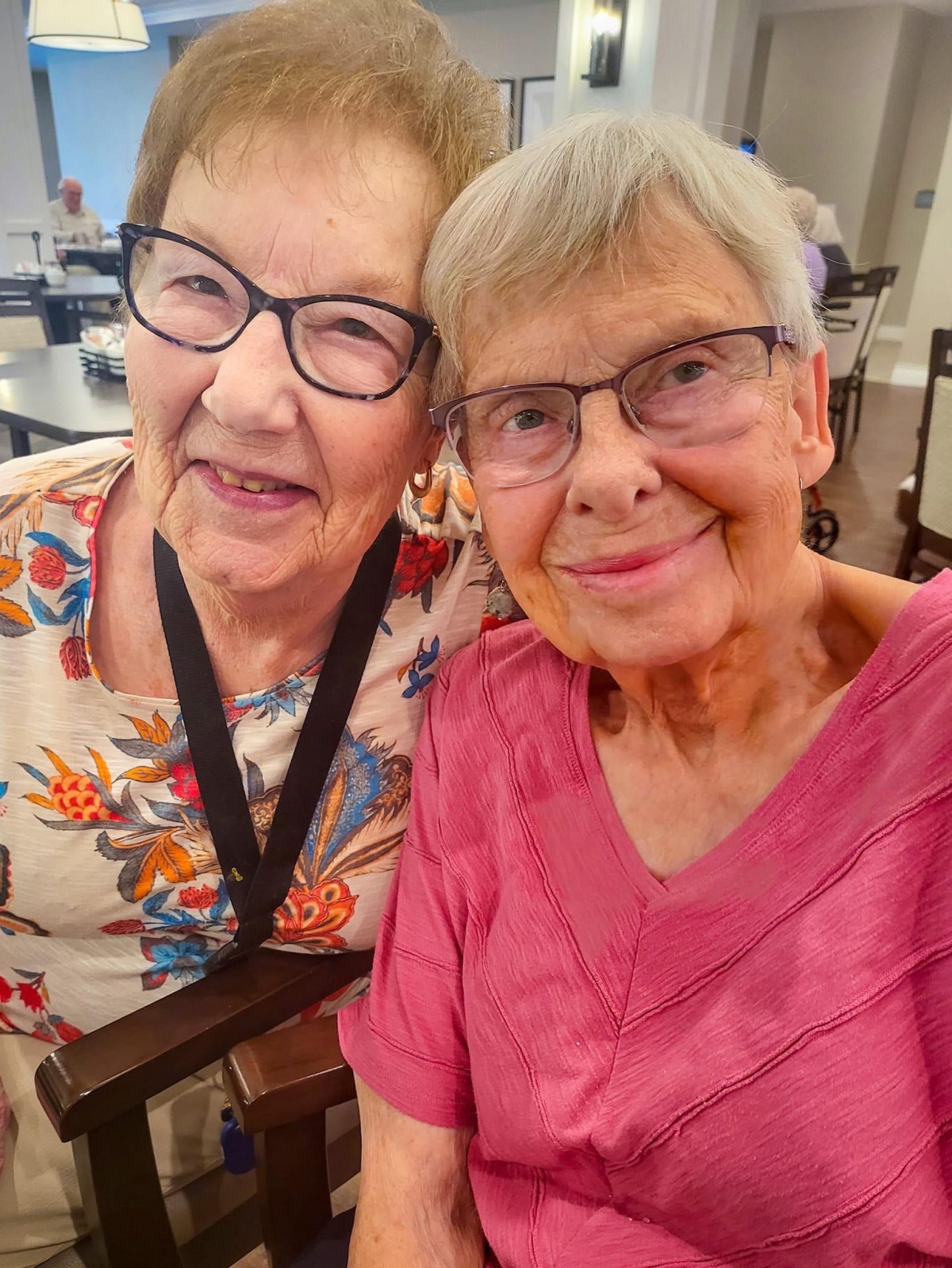 Two elderly women smiling together indoors.