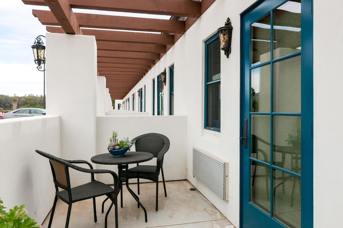 A modern patio with a small table and chairs, accented by a blue door.