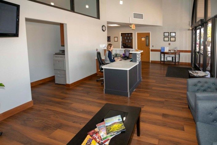 A modern office reception with a desk and waiting area featuring brochures on a table.