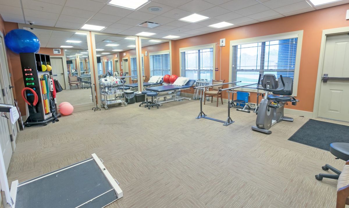 A spacious gym interior with various exercise equipment, including treadmills and bikes.