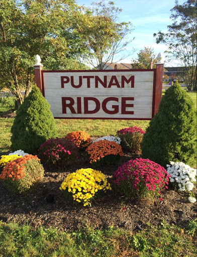 Welcoming sign for Putnam Ridge surrounded by vibrant flowers.