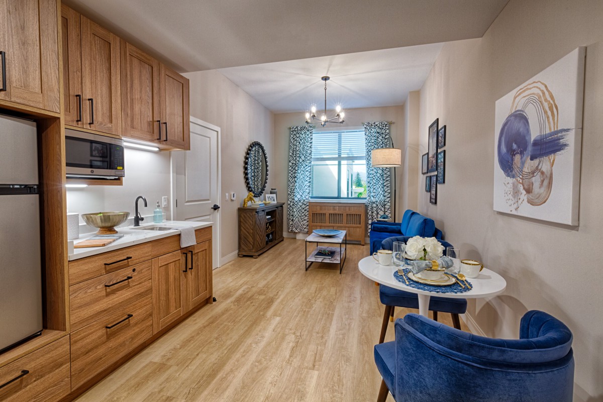 A modern and cozy living space with a compact kitchen area, featuring wooden cabinets, blue furniture, and elegant decor.