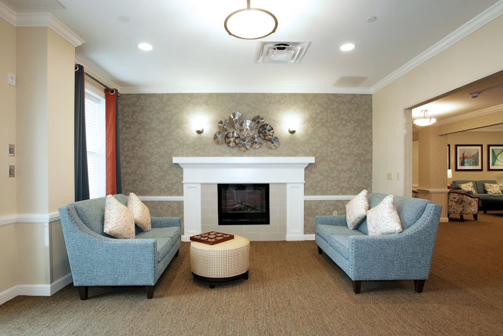 A modern living room featuring a fireplace and two blue sofas arranged around a circular ottoman.