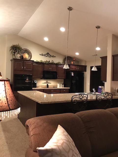 A modern and cozy kitchen with dark cabinets and pendant lighting.