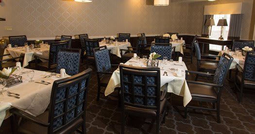 An elegant dining room with neatly set tables and plush chairs.