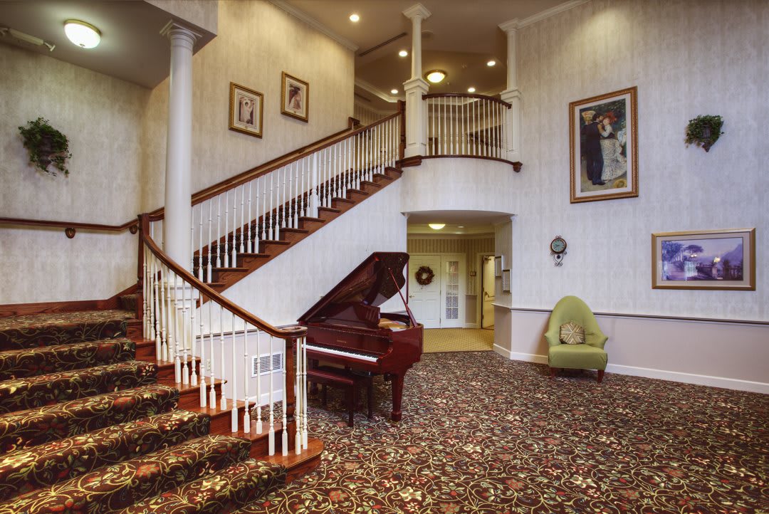 An elegant interior featuring a grand staircase and a piano in the foyer.