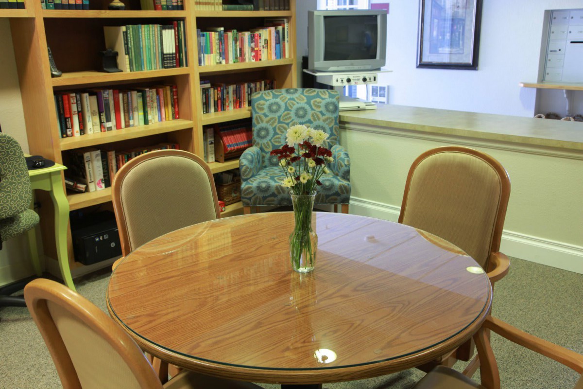 A cozy reading area with a round table and flowers in a library setting.
