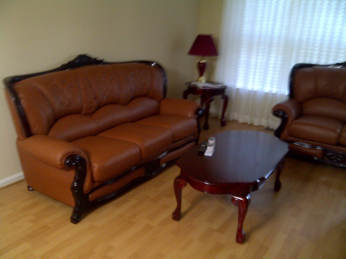 A cozy living room with a leather sofa set, coffee table, and lamp.