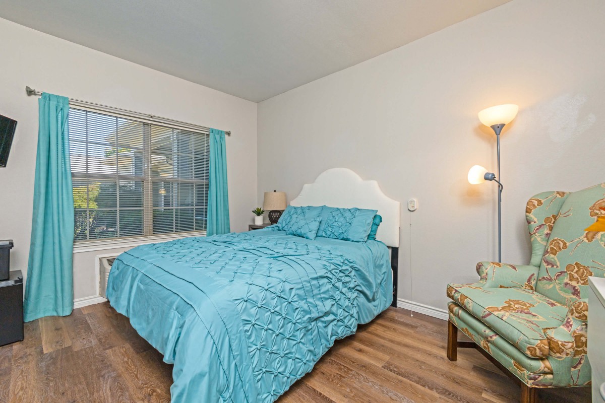 A cozy bedroom with turquoise bedding and a soft glow from the floor lamp.