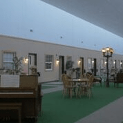 A spacious indoor hallway of a hotel with a piano, tables, and chairs lining the path.