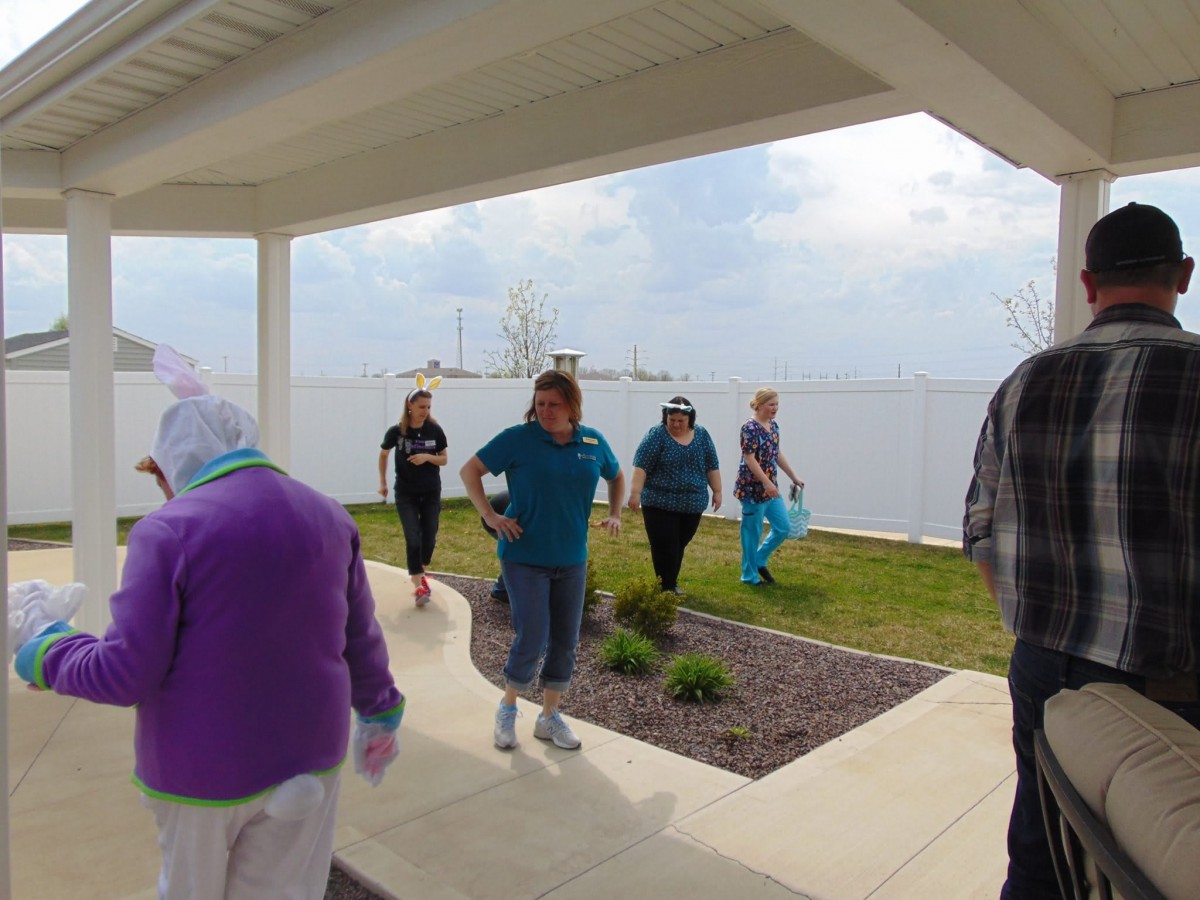 A group of people walking under a shelter by the lake on a cloudy day.