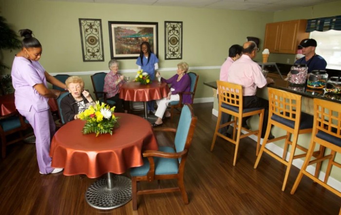 Elderly residents socializing in a care facility with staff assistance.