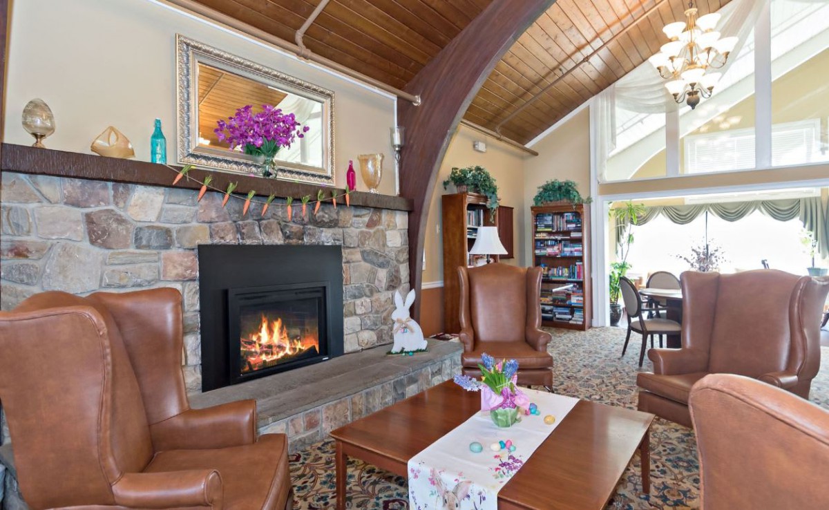 A cozy living room with a stone fireplace, wooden ceiling, and comfortable seating.