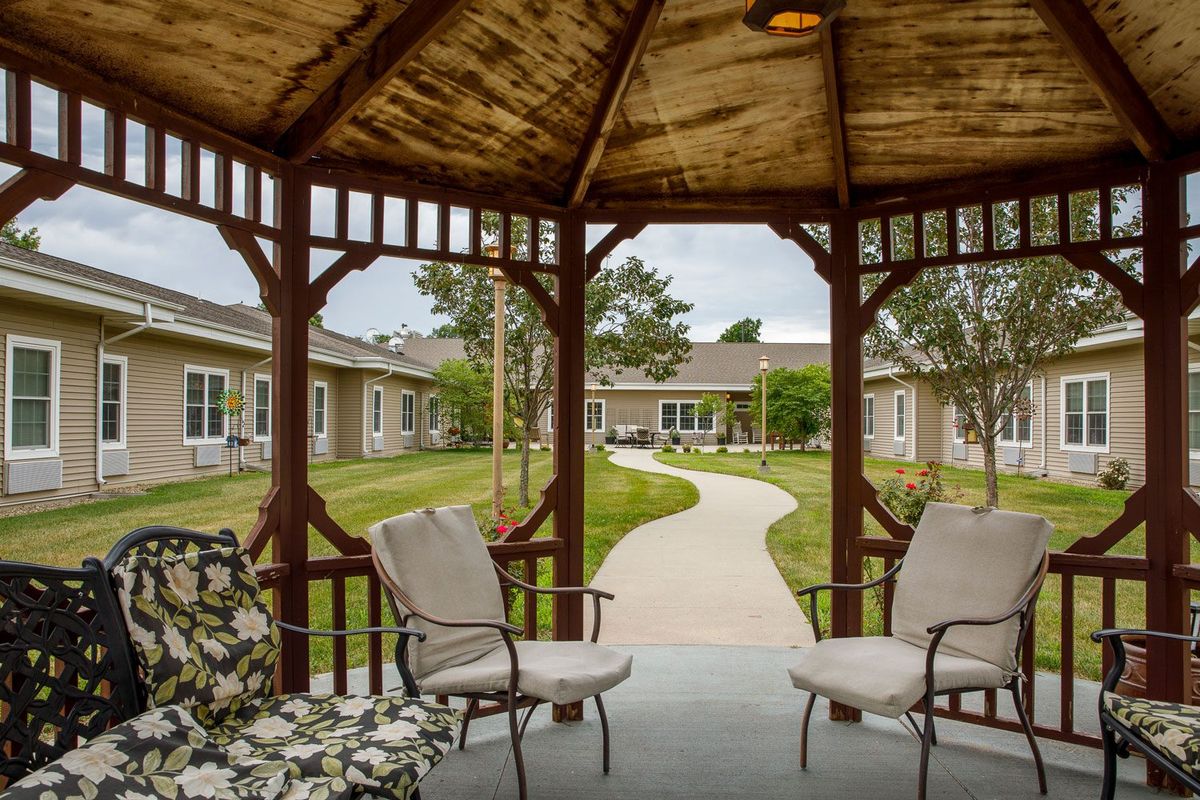 A peaceful gazebo with comfortable seating overlooking a garden pathway.
