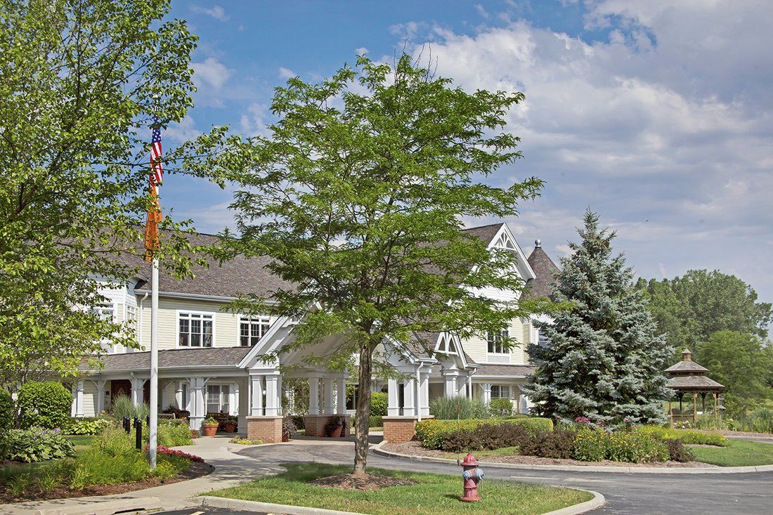 A residential building with a tree in the foreground and a partly cloudy sky.