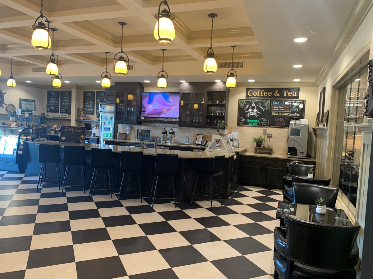 A cozy cafe interior with a checkered floor, bar counter, and hanging lights.