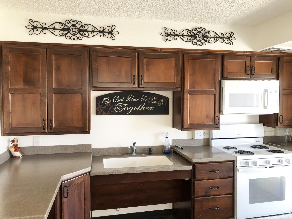 A kitchen with wooden cabinets, decorative wall art, and essential appliances.