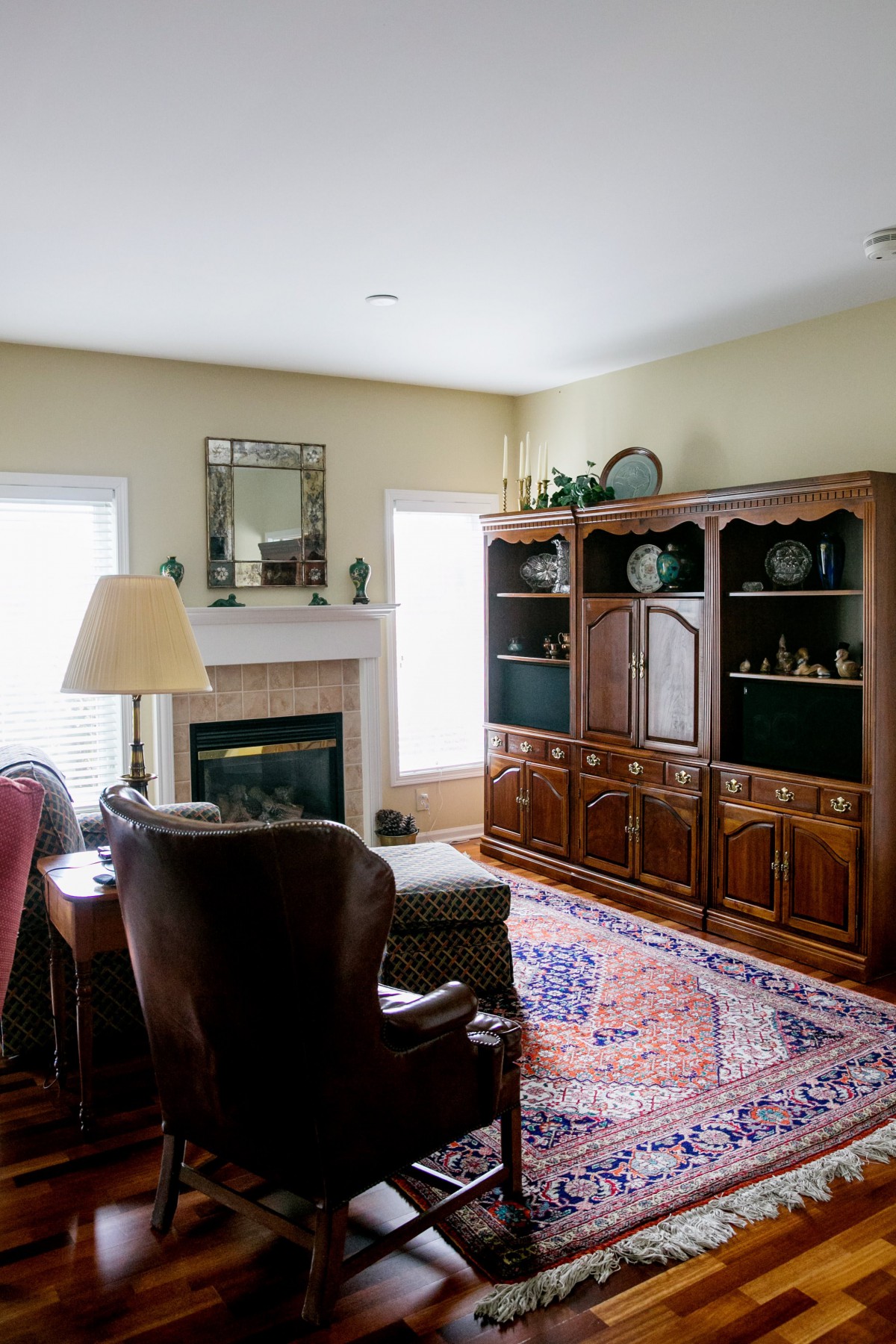 A cozy living room with a fireplace, armchair, and bookshelf.