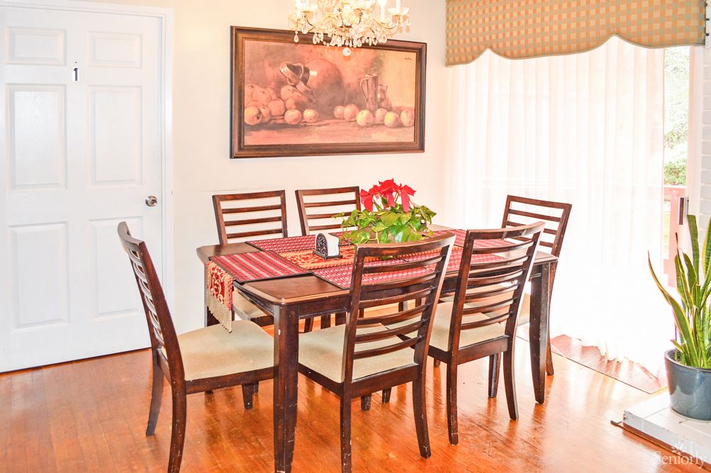 A cozy dining room with a wooden table and chairs, adorned with a chandelier and wall art.
