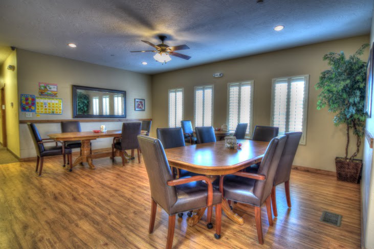A spacious conference room with a large wooden table surrounded by chairs and natural lighting from the windows.