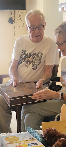 Two individuals engaged in a moment of sharing, examining a box together.