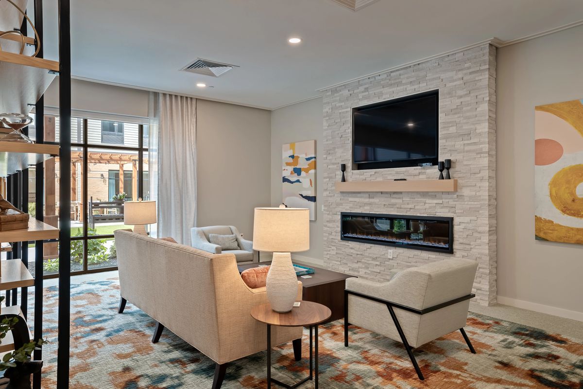 A modern living room with stylish furniture, featuring a stone wall with a mounted television and fireplace.