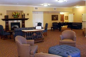 A cozy living room with comfortable seating, a piano, and a fireplace.