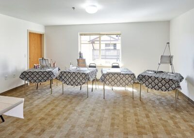 An empty classroom with tables and chairs arranged in rows.