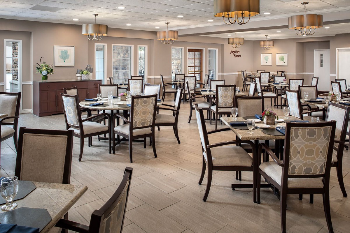An elegant dining area with neatly arranged tables and chairs, featuring warm lighting and tasteful decor.
