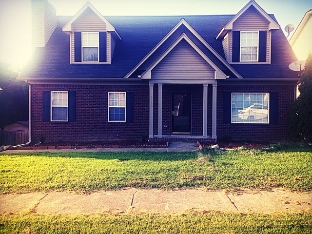 A charming brick house with a well-maintained front yard.