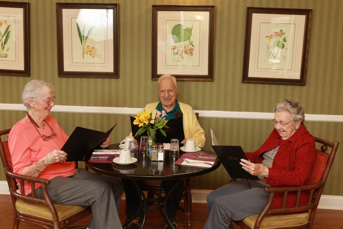 Three elderly friends enjoy a meal together at a restaurant.
