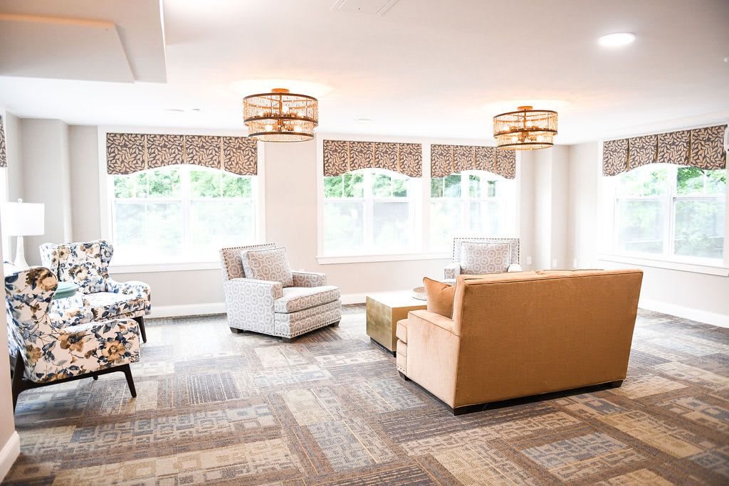 A bright and spacious living room featuring comfortable seating, large windows, and elegant lighting fixtures.