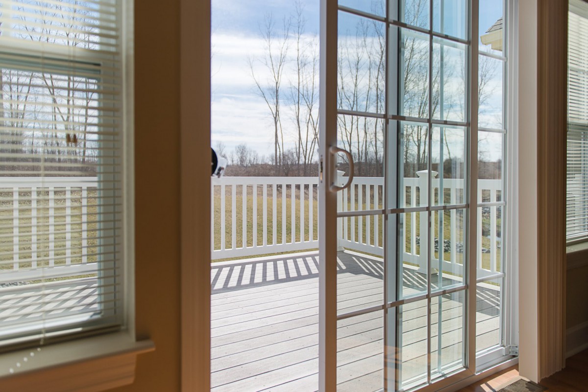 A view through a sliding glass door onto a wooden deck with an outdoor setting.