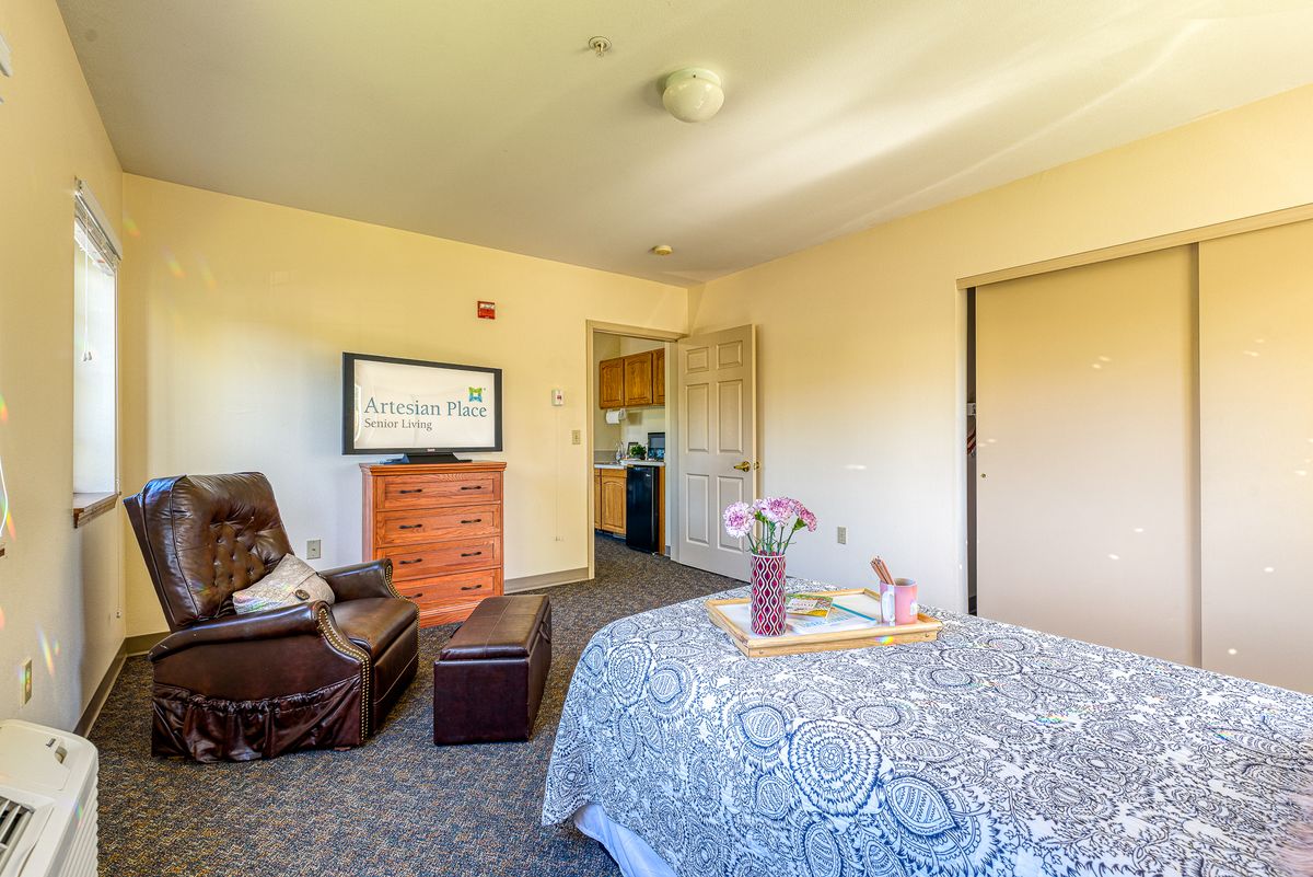 A cozy bedroom interior featuring a bed, TV, and a comfortable chair.