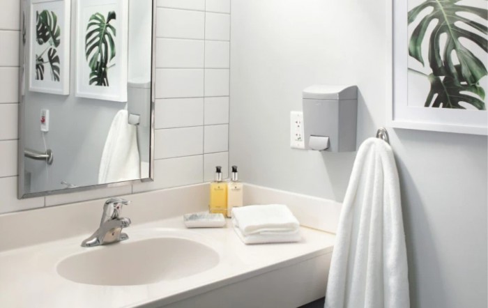 A clean and modern bathroom sink with towels, soap, and a mirror.