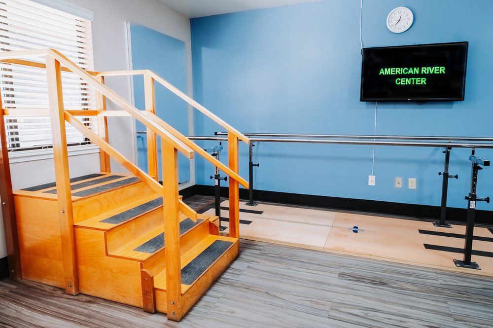 A physical therapy room equipped with stairs and parallel bars for rehabilitation exercises.