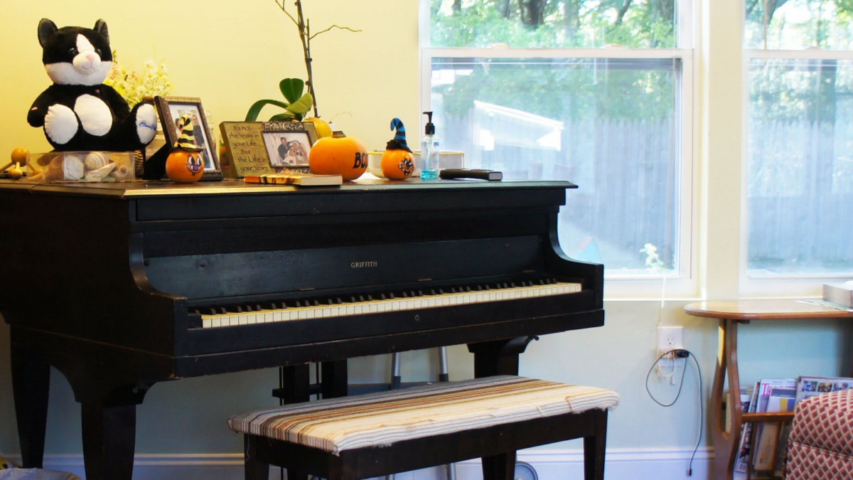 A room with a piano decorated with pumpkins and photos.